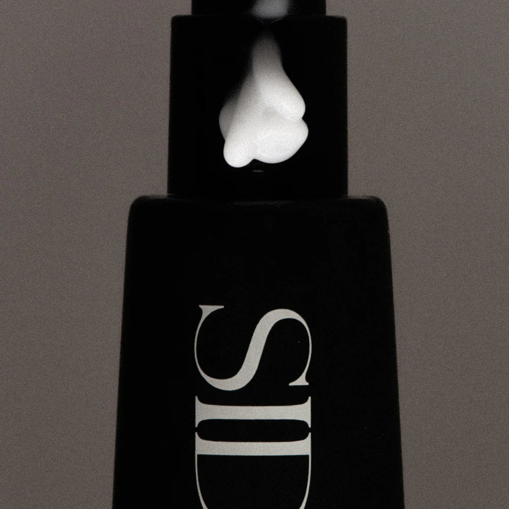 Black SIDIA cosmetic bottle with a white cap on a gray background
