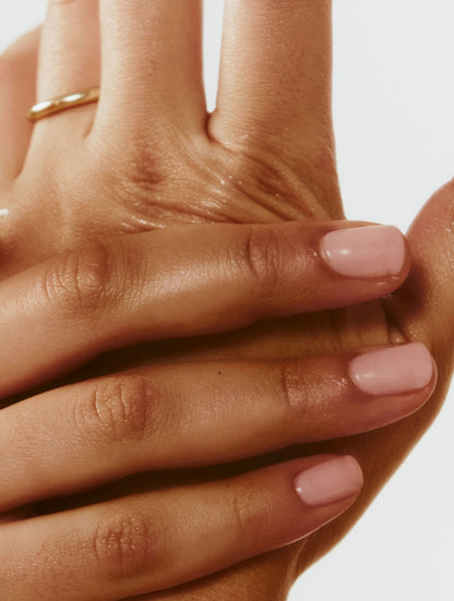 Close-up of a hand with pink nail polish on a neutral background